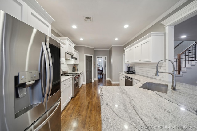 kitchen with stainless steel appliances, a sink, ornamental molding, tasteful backsplash, and light stone countertops