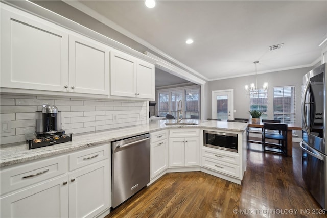 kitchen featuring appliances with stainless steel finishes, a sink, a chandelier, crown molding, and a peninsula