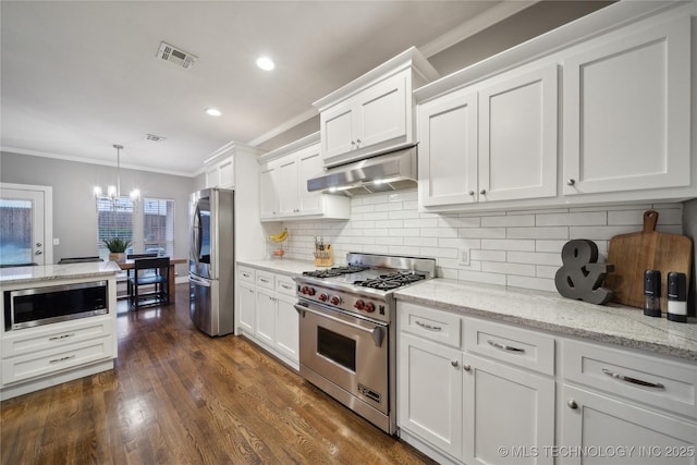 kitchen featuring stainless steel appliances, under cabinet range hood, crown molding, white cabinetry, and a chandelier