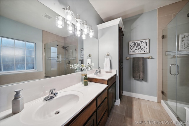 full bathroom featuring a shower stall, double vanity, wood finished floors, and baseboards