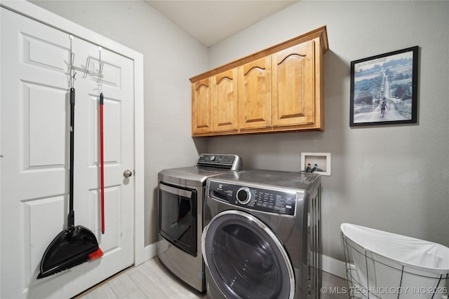 clothes washing area featuring washer and dryer, cabinet space, and baseboards
