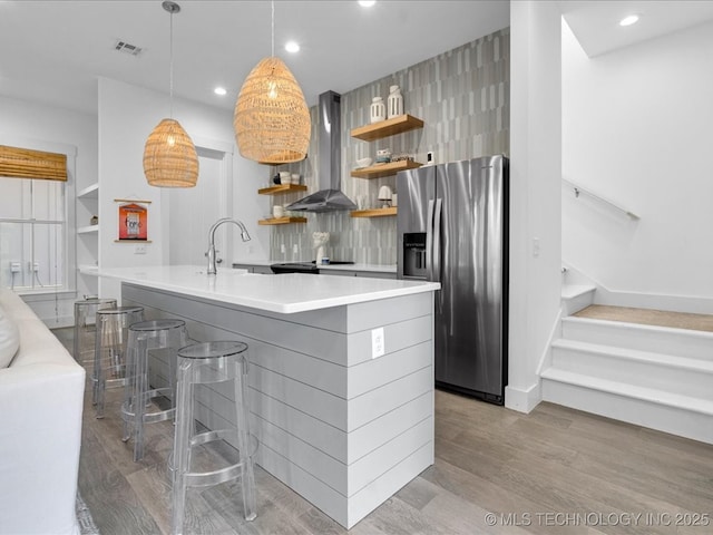 40 Center Ln N, Carlton Landing, OK 74432 - kitchen with stainless steel fridge, wall chimney range hood, open shelves, light wood-style flooring, and light countertops