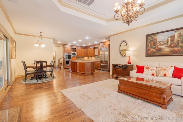 3107 E 88th St, Tulsa, OK 74137 - living room with a chandelier, light wood-style floors, a tray ceiling, ornamental molding, and recessed lighting