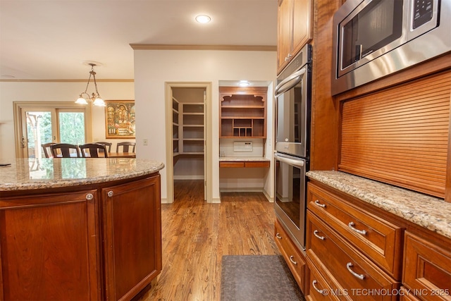 3107 E 88th St, Tulsa, OK 74137 - kitchen featuring appliances with stainless steel finishes, crown molding, brown cabinetry, decorative light fixtures, and light wood-style flooring