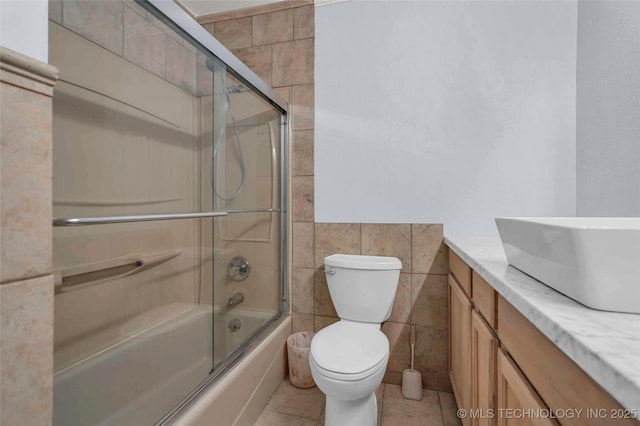 1919 NW 10th St, Ardmore, OK 73401 - bathroom with tile walls, vanity, bath / shower combo with glass door, and toilet