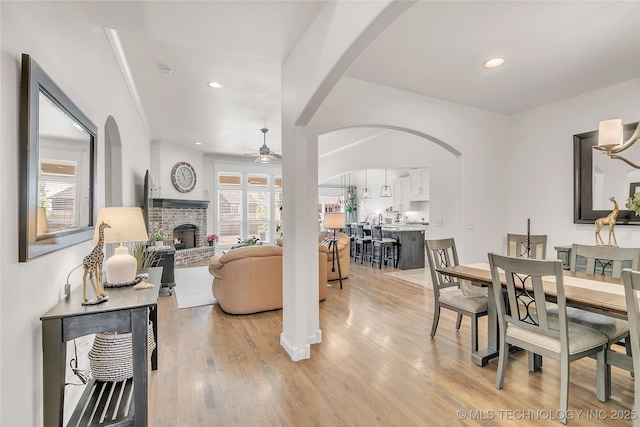 5412 E 122nd St S, Bixby, OK 74008 - dining area with ceiling fan, a brick fireplace, light wood-style flooring, recessed lighting, and arched walkways