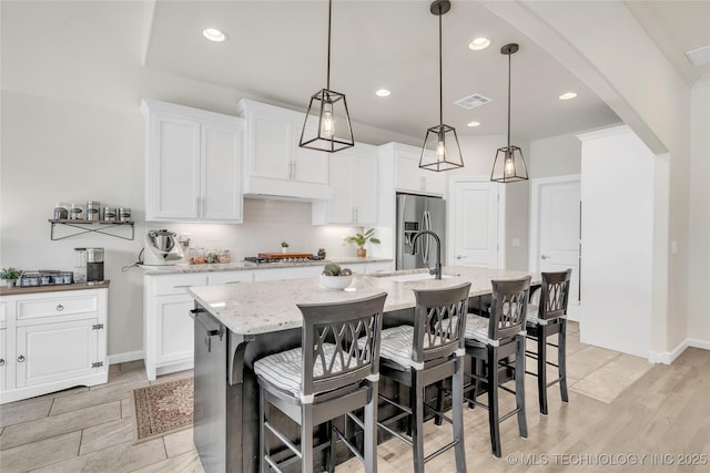 5412 E 122nd St S, Bixby, OK 74008 - kitchen featuring appliances with stainless steel finishes, a kitchen island with sink, tasteful backsplash, light wood-style flooring, and recessed lighting