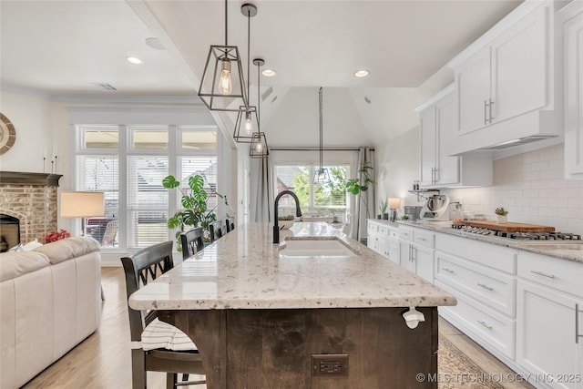 5412 E 122nd St S, Bixby, OK 74008 - kitchen featuring a sink, stainless steel gas stovetop, backsplash, white cabinetry, and light stone counters