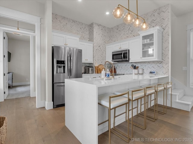 42 Redbud St, Carlton Landing, OK 74432 - kitchen with appliances with stainless steel finishes, light wood-style floors, white cabinets, and decorative backsplash