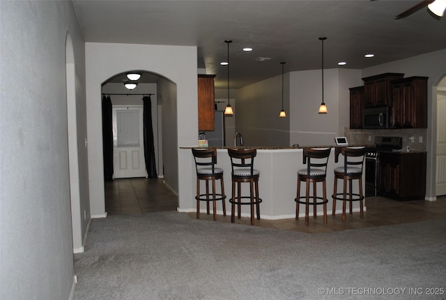 2025 E 134th St S, Bixby, OK 74008 - kitchen with range with gas cooktop, carpet floors, arched walkways, a breakfast bar area, and recessed lighting