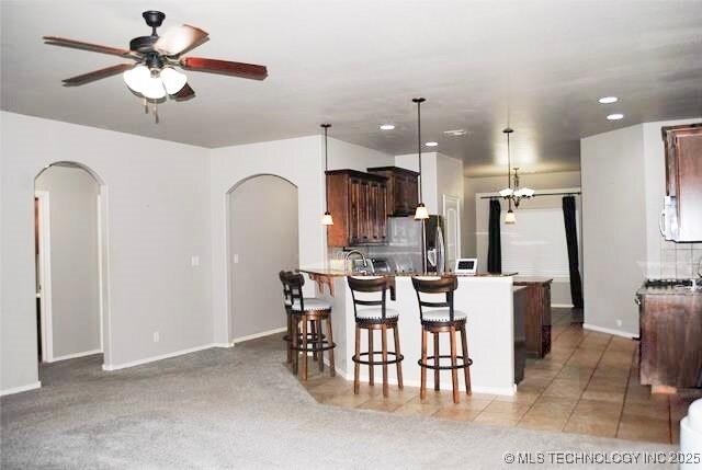 2025 E 134th St S, Bixby, OK 74008 - kitchen featuring arched walkways, stainless steel fridge with ice dispenser, ceiling fan, a breakfast bar, and recessed lighting