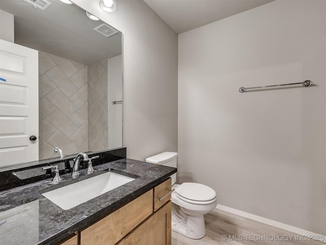 13402 E 124th St, Collinsville, OK 74021 - bathroom with wood finished floors, toilet, vanity, and baseboards