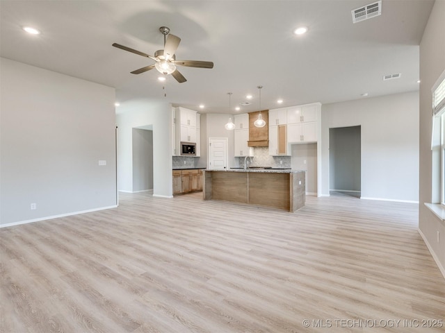 13402 E 124th St, Collinsville, OK 74021 - kitchen with open floor plan, stainless steel microwave, recessed lighting, backsplash, and light wood-style floors