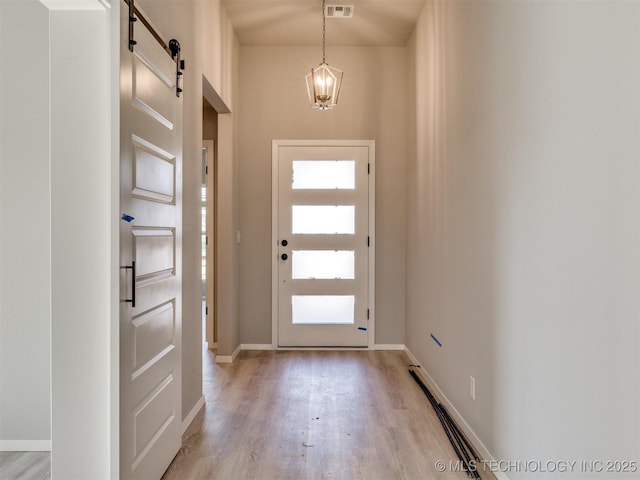 13402 E 124th St, Collinsville, OK 74021 - foyer entrance featuring a barn door, light wood-style flooring, a chandelier, and baseboards