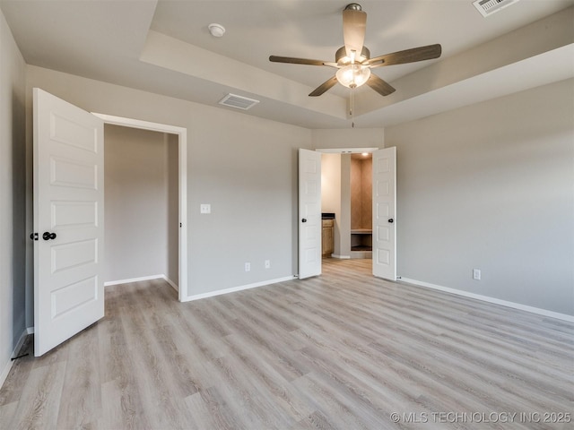 13402 E 124th St, Collinsville, OK 74021 - unfurnished bedroom with baseboards, a raised ceiling, and light wood-type flooring