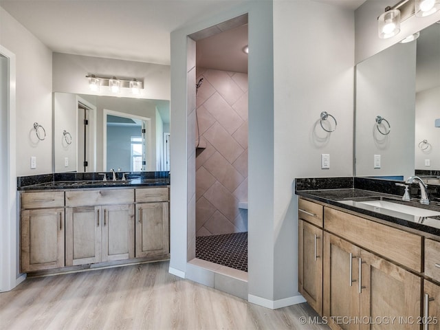 13402 E 124th St, Collinsville, OK 74021 - bathroom featuring wood finished floors, a tile shower, and two vanities