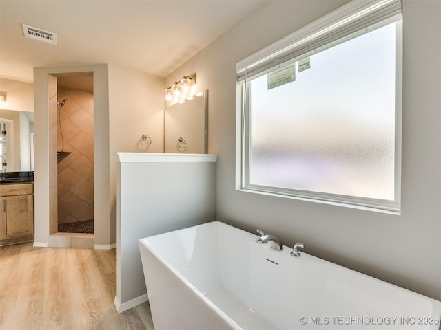 13402 E 124th St, Collinsville, OK 74021 - full bathroom with vanity, a freestanding bath, wood finished floors, and a tile shower