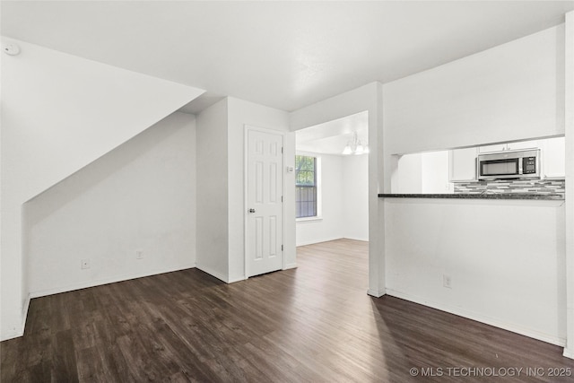 7911 E 66th St Unit 45H, Tulsa, OK 74133 - unfurnished living room featuring wood finished floors, baseboards, and a chandelier