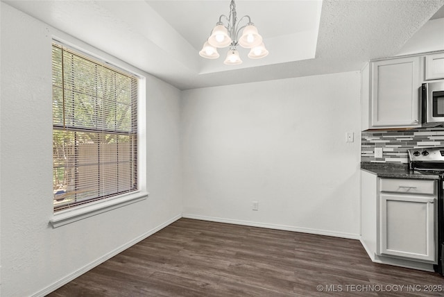 7911 E 66th St Unit 45H, Tulsa, OK 74133 - unfurnished dining area featuring a chandelier, dark wood-style flooring, and baseboards
