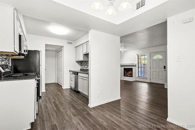 7911 E 66th St Unit 45H, Tulsa, OK 74133 - kitchen with stainless steel appliances, dark countertops, backsplash, open floor plan, and dark wood-style floors