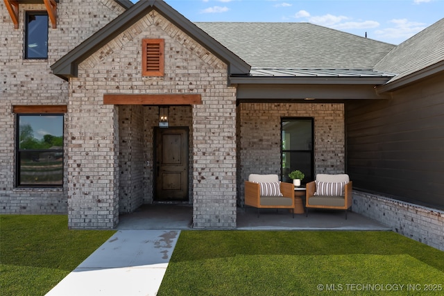 16306 E 102nd St, Owasso, OK 74055 - property entrance with brick siding, roof with shingles, a lawn, a standing seam roof, and covered porch