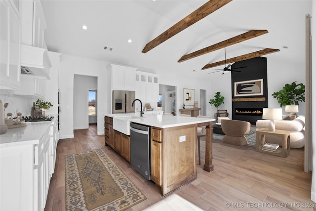 16306 E 102nd St, Owasso, OK 74055 - kitchen featuring stainless steel appliances, a sink, a ceiling fan, beamed ceiling, and a fireplace