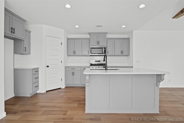 11412 E 93rd Pl, Owasso, OK 74055 - kitchen featuring stainless steel microwave, gray cabinetry, gas range, tasteful backsplash, and recessed lighting