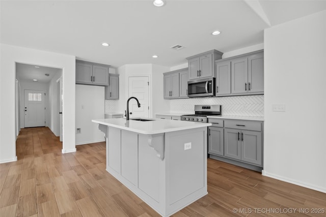 11412 E 93rd Pl, Owasso, OK 74055 - kitchen with stainless steel appliances, gray cabinets, a sink, backsplash, and a center island with sink