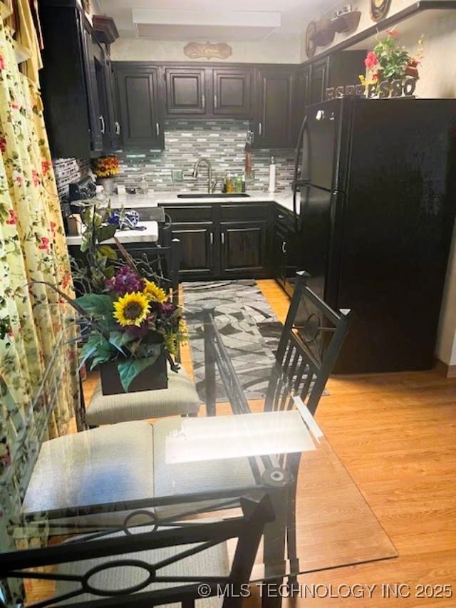 1417 Leisure Rd, Grove, OK 74344 - kitchen featuring freestanding refrigerator, a sink, light countertops, light wood finished floors, and decorative backsplash