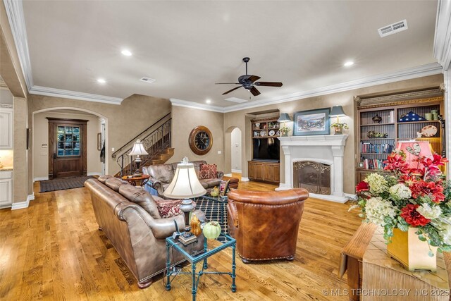 10942 S 93rd E Ave, Bixby, OK 74133 - living area featuring arched walkways, a fireplace with raised hearth, stairs, light wood-style flooring, and ceiling fan