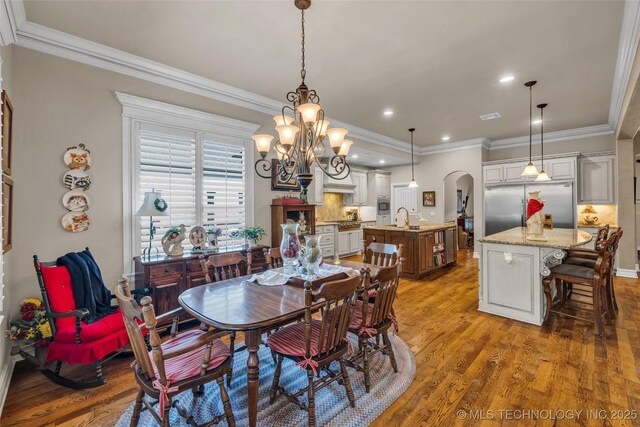 10942 S 93rd E Ave, Bixby, OK 74133 - dining space featuring arched walkways, wood finished floors, crown molding, a chandelier, and recessed lighting