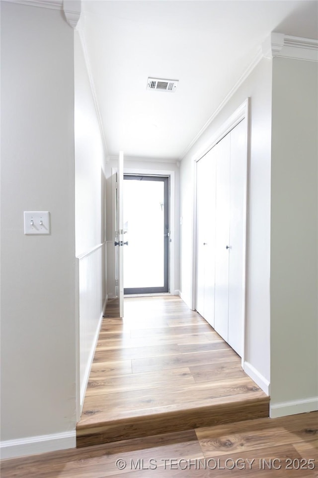 corridor with crown molding, light wood-style flooring, and baseboards