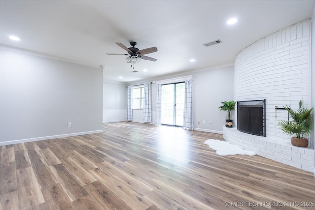 unfurnished living room with a ceiling fan, recessed lighting, ornamental molding, wood finished floors, and a fireplace