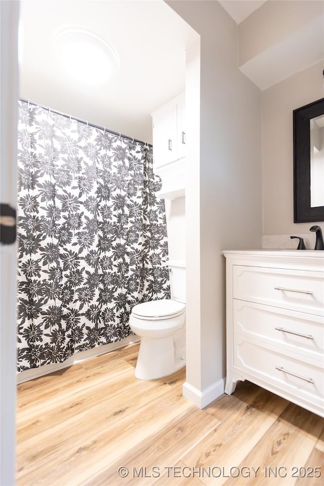 bathroom featuring toilet, wood finished floors, curtained shower, and vanity