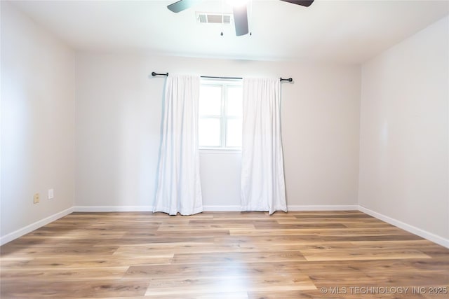 spare room with a ceiling fan, light wood finished floors, and baseboards