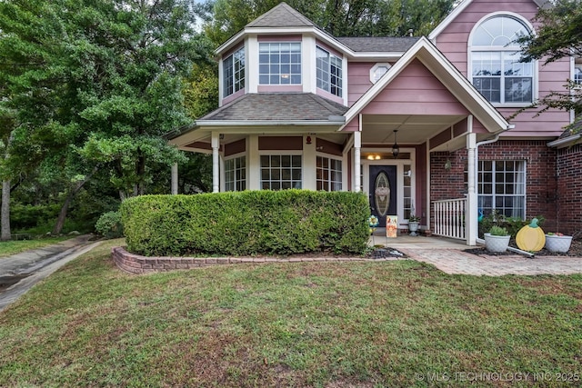 traditional-style home featuring a front yard, a shingled roof, and brick siding