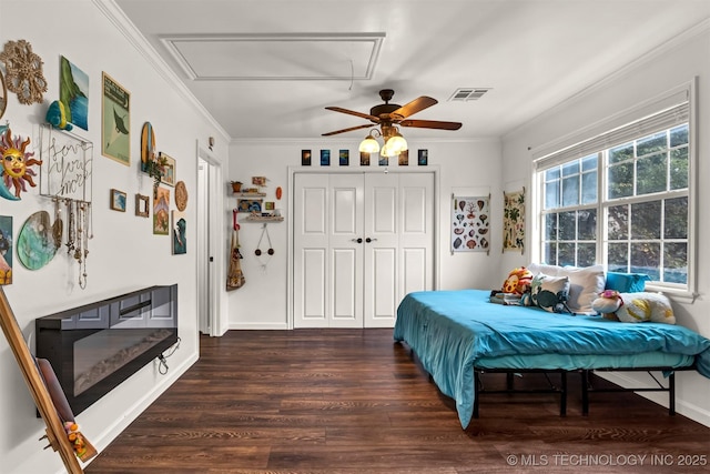 bedroom with attic access, wood finished floors, crown molding, ceiling fan, and a closet