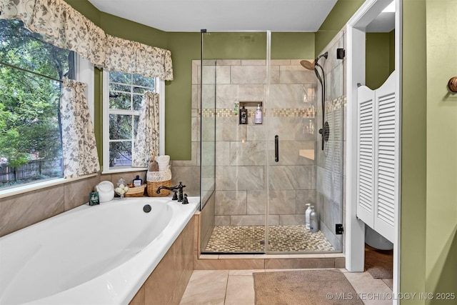 bathroom with healthy amount of natural light, tile patterned floors, a bath, and a shower stall