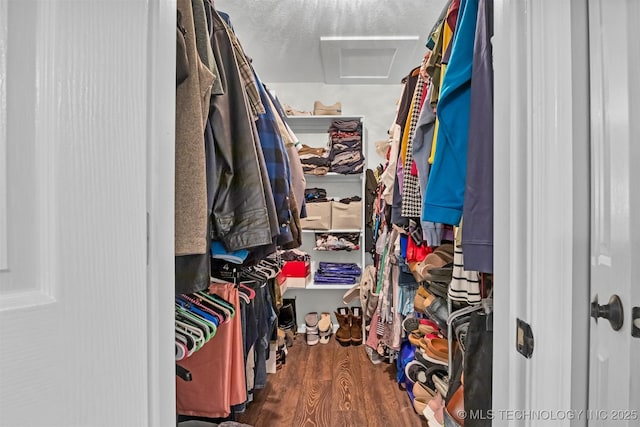 walk in closet with attic access and wood finished floors