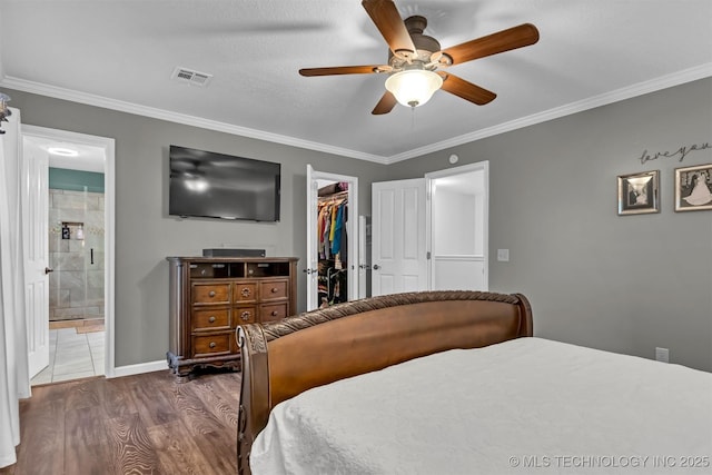 bedroom with a spacious closet, dark wood finished floors, ornamental molding, a closet, and ceiling fan