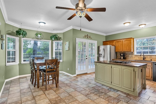 kitchen featuring a sink, appliances with stainless steel finishes, a center island, ceiling fan, and decorative backsplash