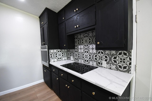 96358 S 4531, Vian, OK 74962 - kitchen with dark cabinets, stainless steel oven, black electric stovetop, light wood-style floors, and decorative backsplash