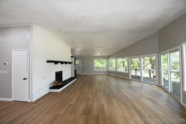 96358 S 4531, Vian, OK 74962 - unfurnished living room with lofted ceiling, baseboards, a brick fireplace, a textured ceiling, and wood-type flooring