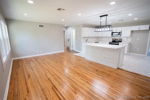 4024 E 25th St, Tulsa, OK 74114 - kitchen with appliances with stainless steel finishes, white cabinets, decorative backsplash, hanging light fixtures, and light countertops