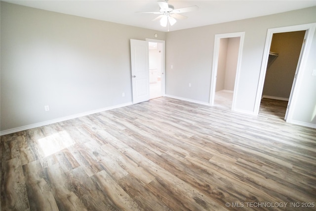4024 E 25th St, Tulsa, OK 74114 - unfurnished bedroom featuring wood finished floors, a walk in closet, baseboards, a ceiling fan, and a closet