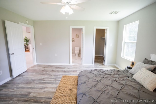 4024 E 25th St, Tulsa, OK 74114 - bedroom with wood finished floors, a walk in closet, baseboards, ensuite bathroom, and a ceiling fan