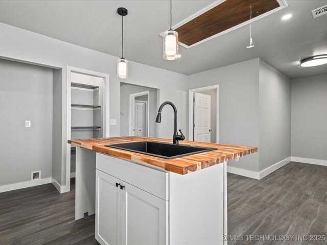 241 NE Debell Ave, Bartlesville, OK 74006 - kitchen with butcher block counters, a sink, white cabinets, and dark wood-style floors