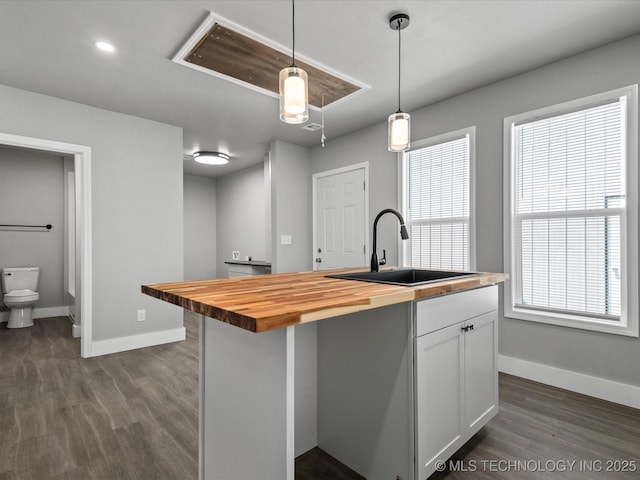241 NE Debell Ave, Bartlesville, OK 74006 - kitchen with wooden counters, a sink, baseboards, and white cabinets