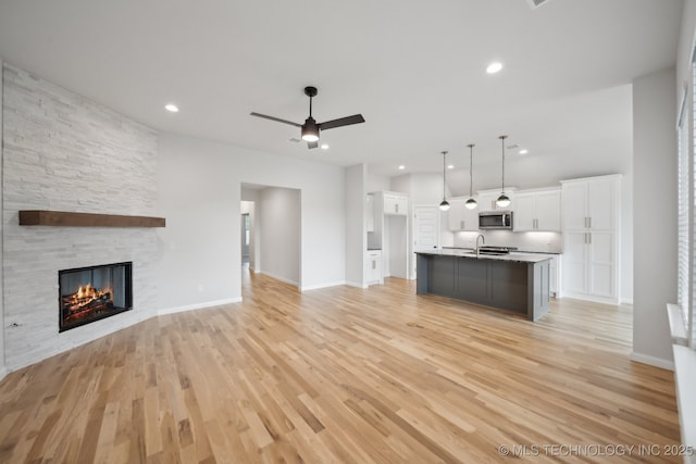 1305 N Dogwood Ave, Broken Arrow, OK 74012 - unfurnished living room featuring a sink, a fireplace, ceiling fan, light wood-style floors, and recessed lighting