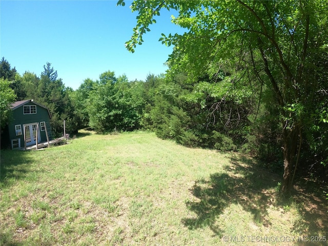 808 N Norfolk Rd, Yale, OK 74085 - view of grassy yard featuring french doors, a forest view, and an outbuilding